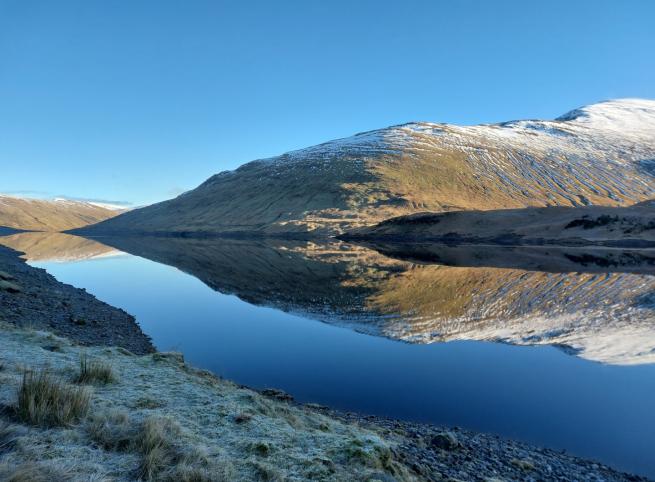 Reflection of mountains in still highland loch